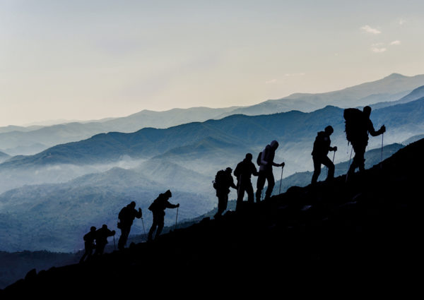 Silhouettes of hikers climbing the mountain at Dusk